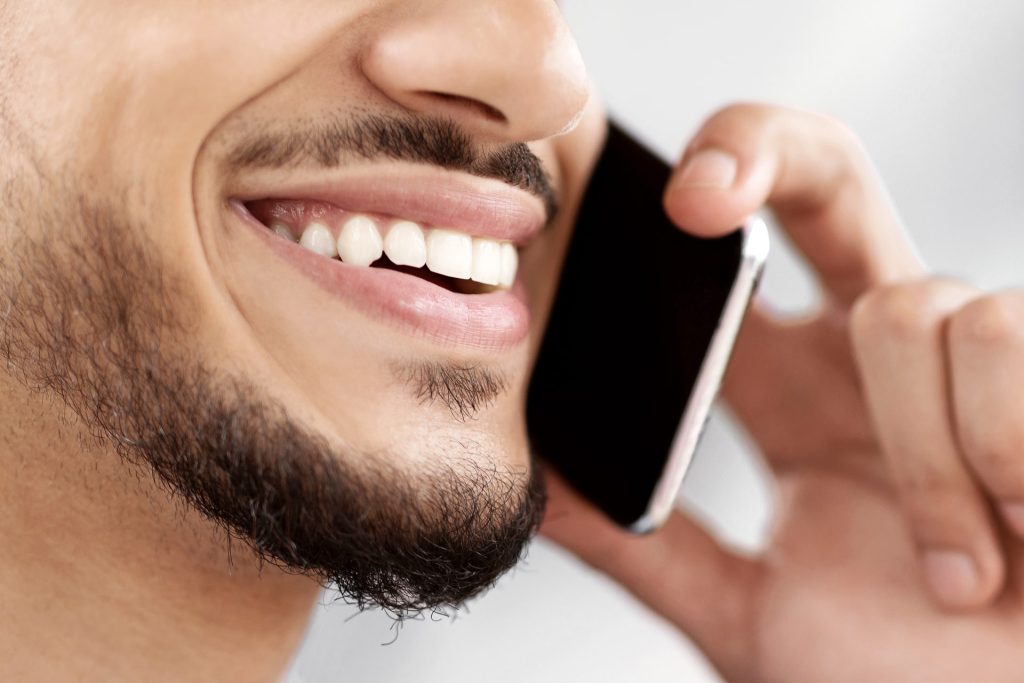 Phone call. Closeup shot of smiling man talking on cellphone, unrecognizable middle eastern guy enjoying mobile communication, having pleasant conversation, selective focus, copy space.