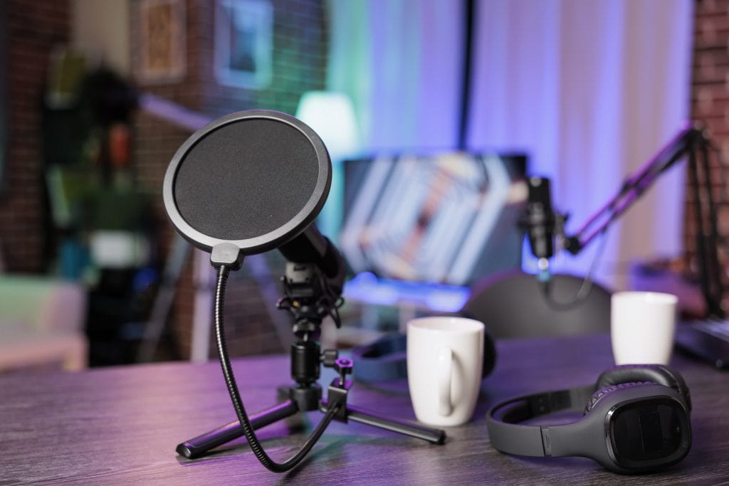 Close up shot of podcast microphone used to record discussions for online livestreaming channel. Streaming sound capturing and recording technology in empty living room with neon lights.