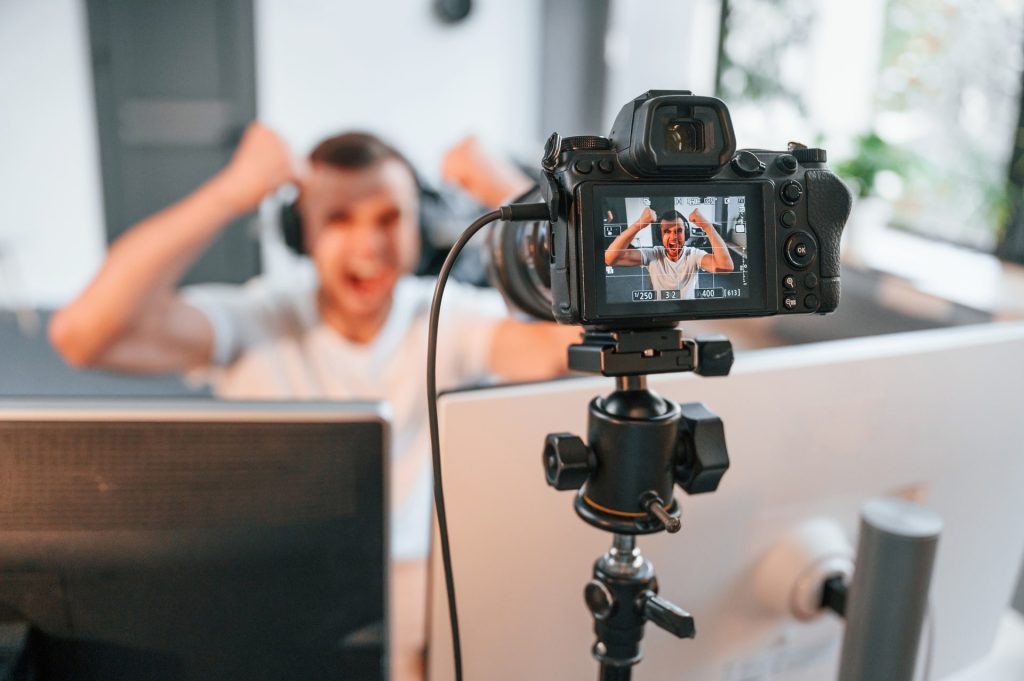 Process of recording. Young man playing and streaming the first person shooter game.